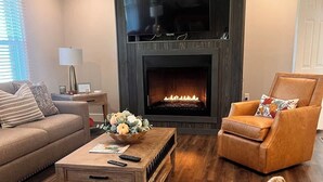 Ein Wohnzimmer mit Kamin, einer Couch, einem Couchtisch und einem Sessel.