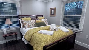 Ein Schlafzimmer mit einem Bett, einem Deckenventilator, einer Nachttischlampe und einem Fenster mit Jalousien.