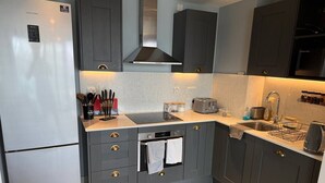 Una cocina moderna con gabinetes grises, un refrigerador de acero inoxidable, horno empotrado y un fregadero.