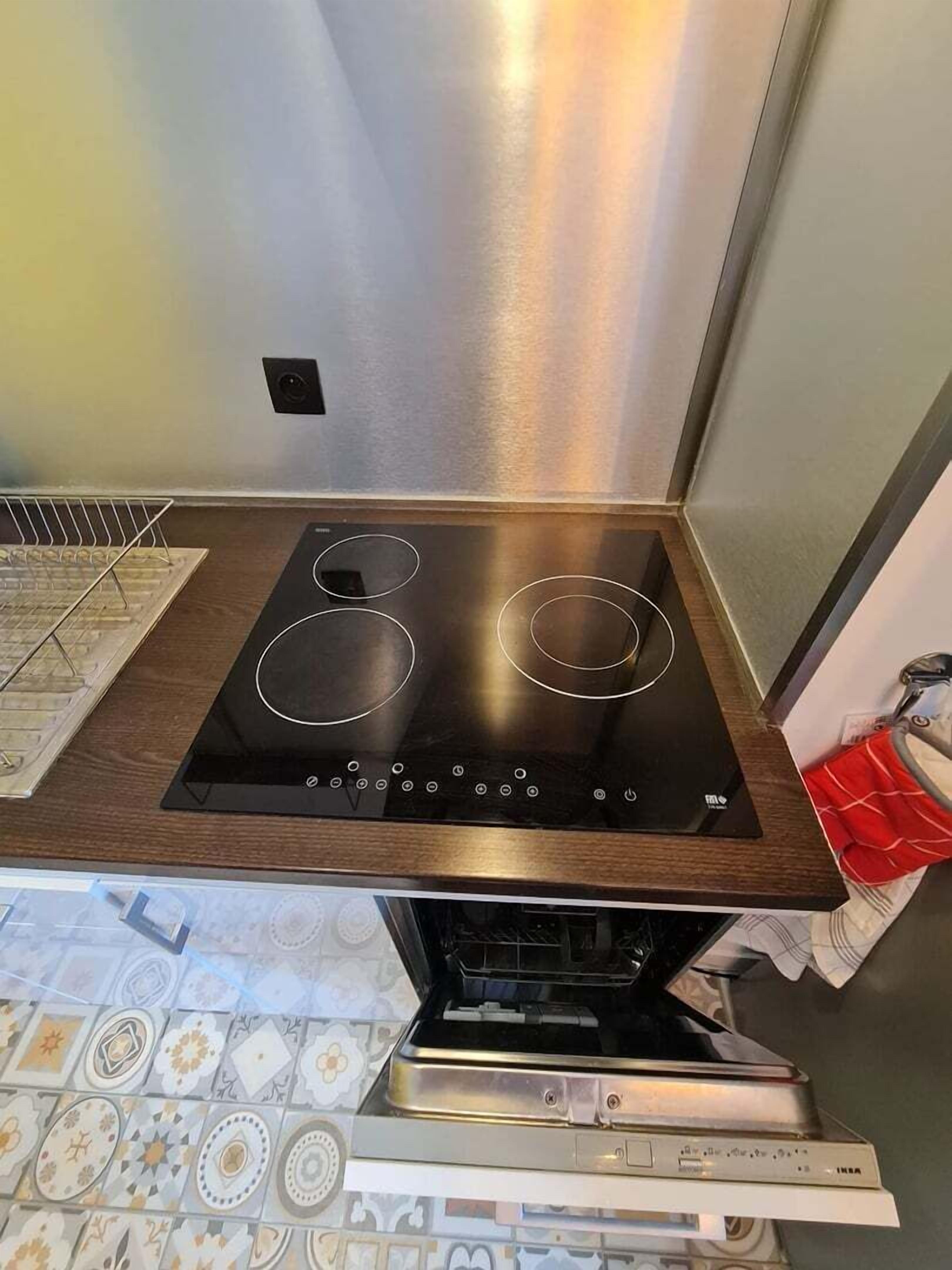 A kitchen with a black induction cooktop, a stainless steel range hood, and a built-in oven.