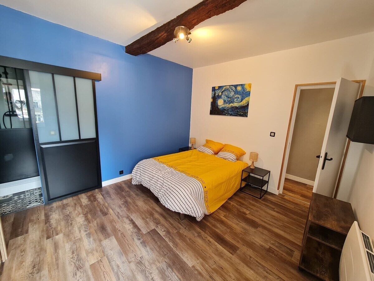 A bedroom with a bed, a painting on the wall, and a door.