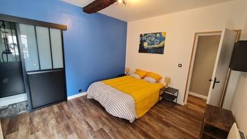 A bedroom with a bed, a painting on the wall, and a door.