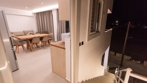 Un intérieur moderne comprenant un coin repas, une cuisine et un escalier menant à un balcon extérieur.