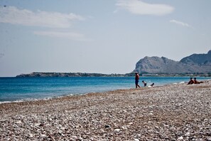 A pebbled beach with people relaxing and walking along the shore. - Sinani Villas Rhodes - Serene Cozy Getaway (Rhodes)