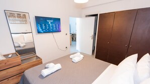 Una habitación de hotel moderna con una cama, un tocador de madera, un espejo grande y un televisor de pantalla plana montado en la pared.