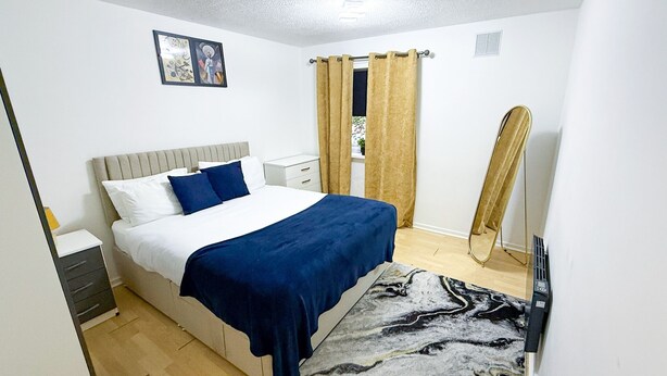 Een slaapkamer met een bed, nachtkastjes, een spiegel en een raam met gordijnen.