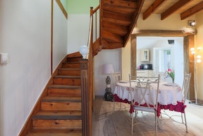 A wooden staircase leading to a dining area with a table set for two, a lamp, and a chair.