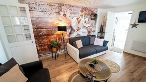 A modern living room with a dark grey sofa, a round coffee table, and a wall mural.