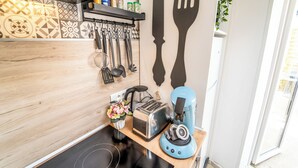 A kitchen with a wooden countertop, a toaster, a coffee maker, and hanging utensils.