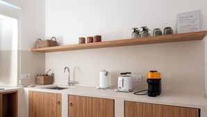 Et moderne køkken med træskabe, en hvid bordplade og en træhylde med glas og en kurv.