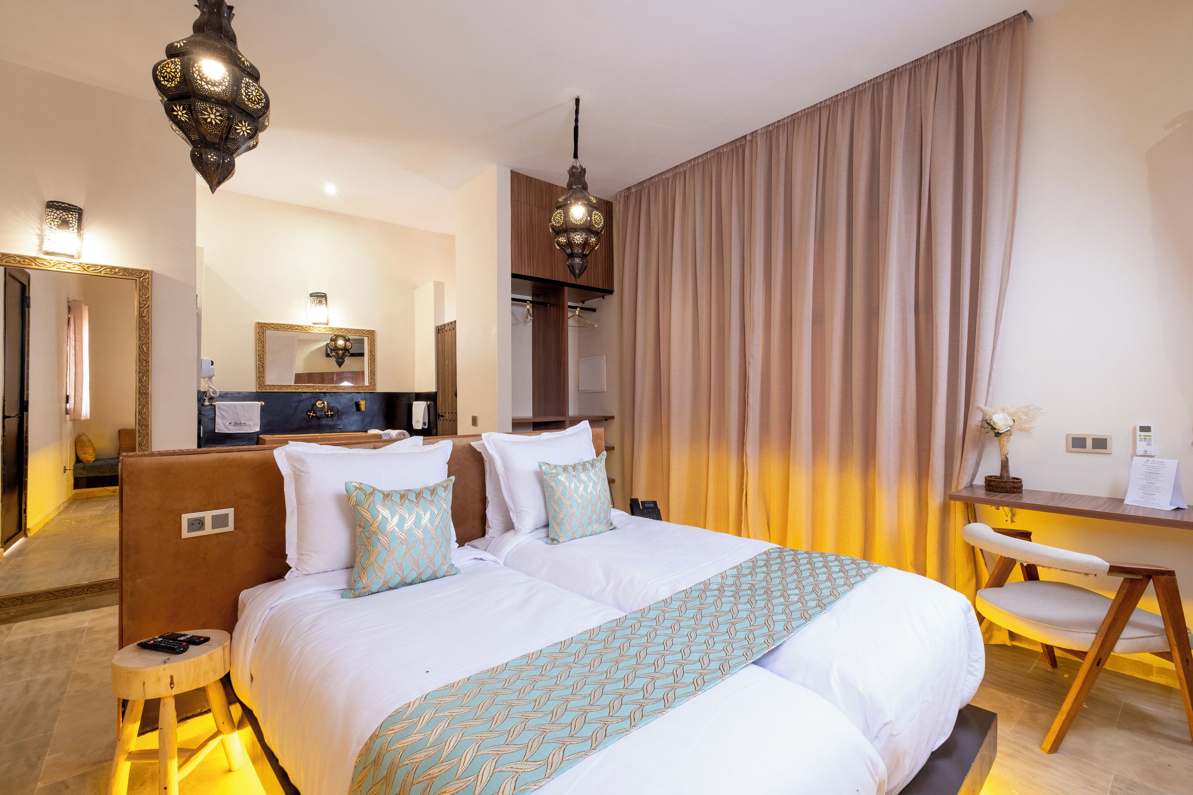 Quarto de hotel com uma cama grande, mesas de cabeceira, uma escrivaninha e uma cadeira.