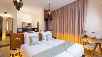 Quarto de hotel com uma cama grande, mesas de cabeceira, uma escrivaninha e uma cadeira.