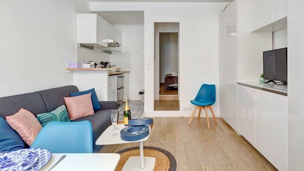 Eine moderne Wohnung mit Wohnzimmer, einer kleinen Küche, einem Essbereich und einem Schlafzimmer.
