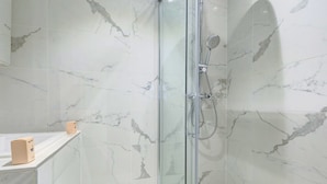 Eine begehbare Duschkabine mit Handbrause und am Wand montierter Armatur.