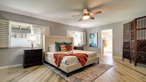 A bedroom with a large bed, a ceiling fan, and a view of the outside through a window with shutters. - North Scottsdale Gem w/ Pool , Hot Tub, Putting Green! (Scottsdale)