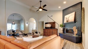A spacious living room with a leather sofa, a fireplace, and a ceiling fan. - North Scottsdale Gem w/ Pool , Hot Tub, Putting Green! (Scottsdale)