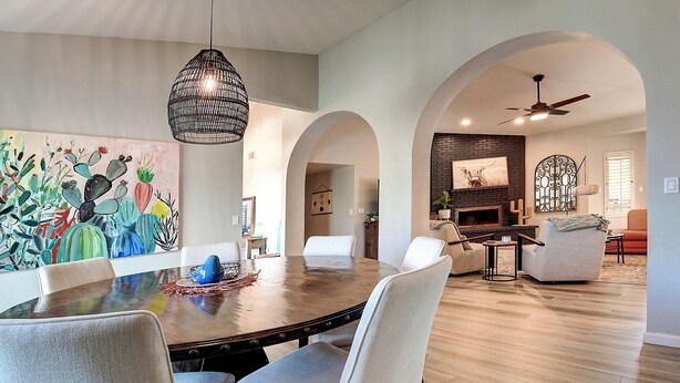 A dining area with a round table, white chairs, a hanging light fixture, and a painting on the wall. - North Scottsdale Gem w/ Pool , Hot Tub, Putting Green! (Scottsdale)