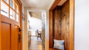 A hallway with wooden flooring, a stone wall, and a wooden bench with a pillow. - Tamarron Condo w/ Pools, Sauna & Fireplace (Durango)