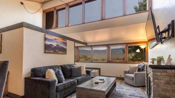 A modern living room with a large window, a fireplace, and a cozy seating area. - Tamarron Condo w/ Pools, Sauna & Fireplace (Durango)