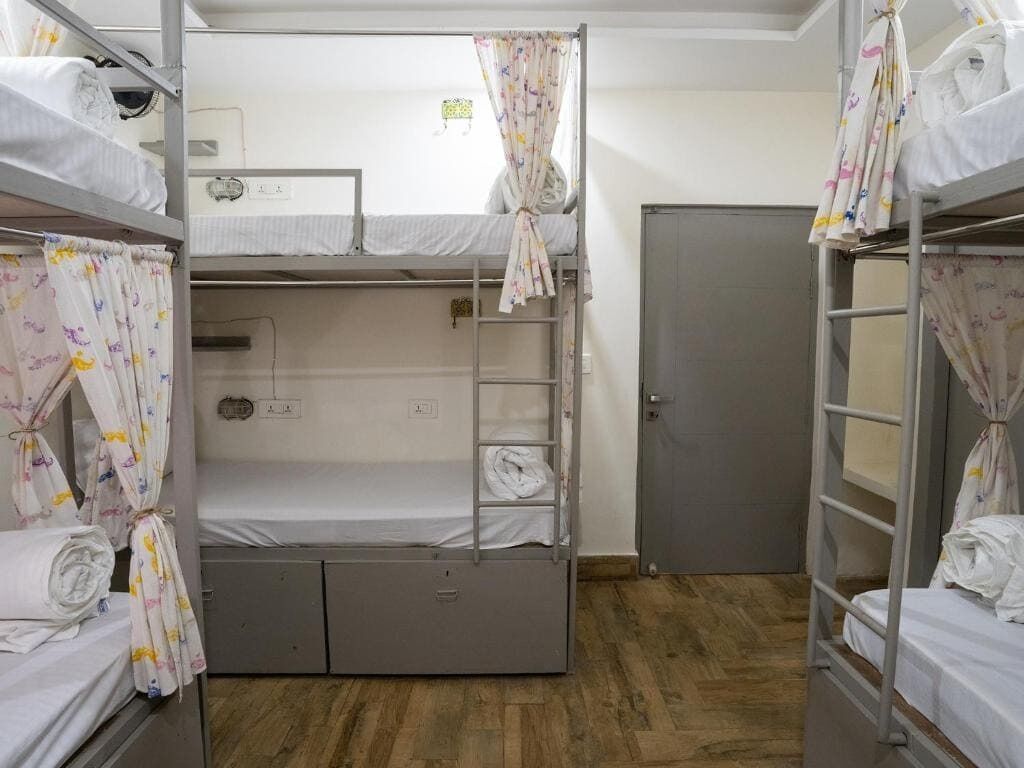 A dormitory room with bunk beds, a wardrobe, and a door.