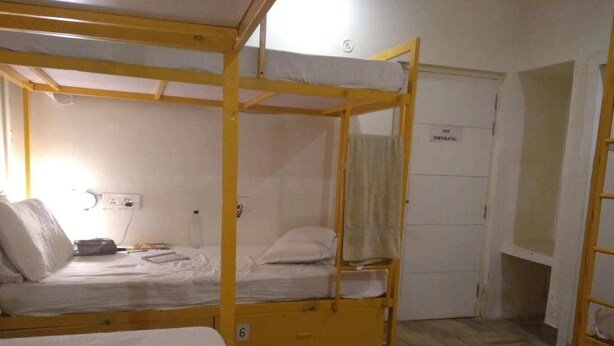 Une chambre de dortoir avec des lits superposés, un bureau, une chaise et une armoire.