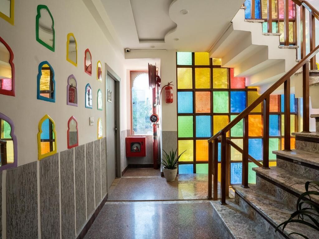 Un couloir orné de vitraux colorés, un escalier et une plante en pot.