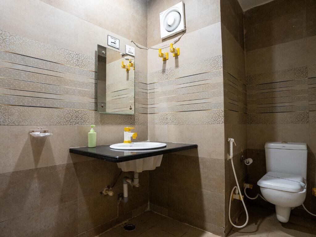 A compact bathroom with a sink, mirror, and toilet.