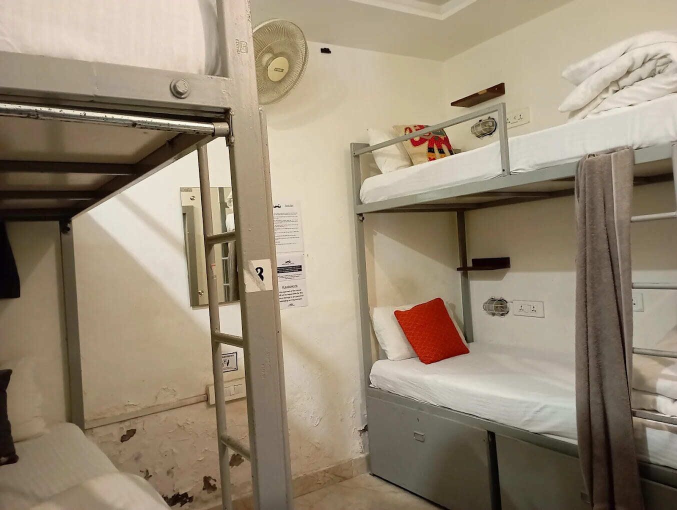 A bunk bed room with a ladder, a fan, and a notice on the wall.