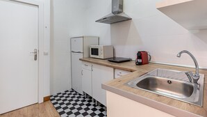 A compact kitchen with white cabinets, a microwave, a toaster, and a sink.
