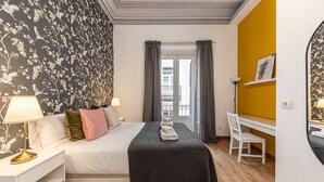 A hotel room with a bed, a desk, a chair, and a window with curtains.