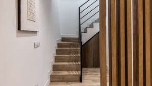 A staircase with wooden steps and a black railing, leading to an upper floor. - Waou Chamberi VIII - Short Term Rental (Madrid)