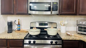 A kitchen with a stove, microwave, and a coffee maker.