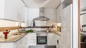A modern kitchen with white cabinets, a stainless steel range hood, a built-in oven, and a dishwasher. - Waou La Latina V - Short Term Rental (Madrid)