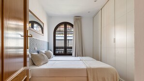 A bedroom with a bed, a window with curtains, and a view of the outside. - Waou Chamberi X - Short Term Rental (Madrid)