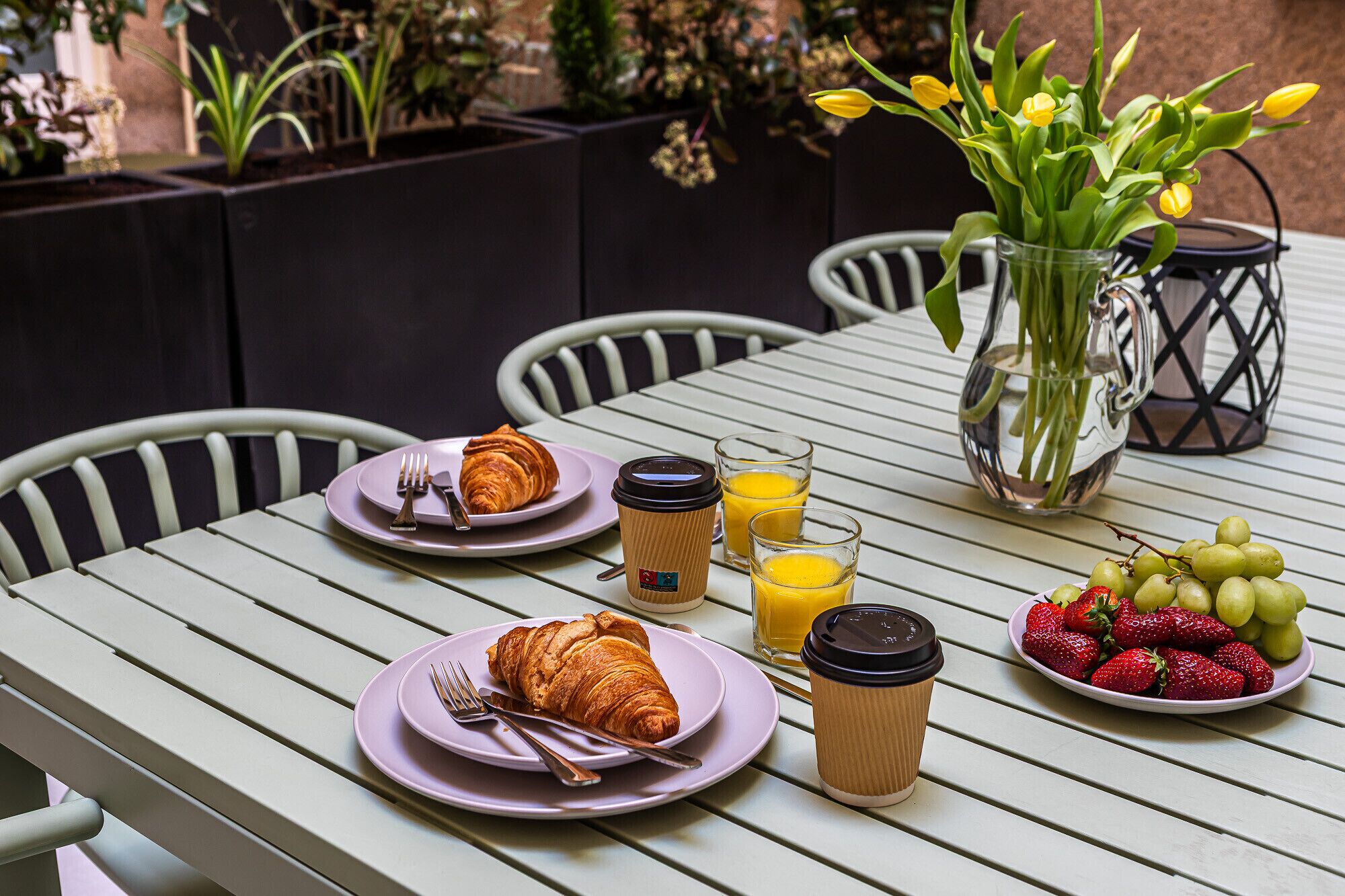 A table set with croissants, coffee, juice, and fruit.