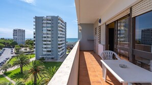Ein Balkon mit Blick auf das Meer, ein weißer Tisch und ein Stuhl.