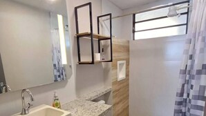 A modern bathroom with a granite countertop, a white sink, a toilet, and a shower area with a striped curtain. - Studio Barreto Leme 72 (Campinas)