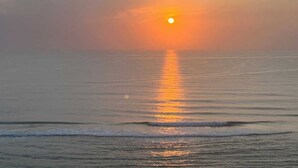 A sunset over a calm sea with a clear horizon. - Beachfront Studio - King Bed & Direct Ocean View (Daytona Beach)