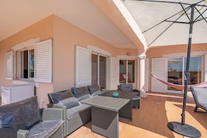 An outdoor patio with wicker furniture, a table, and a hammock.