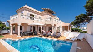 Un edificio a due piani con piscina, area salotto all'aperto e un balcone.