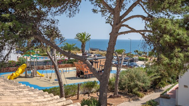 Una località balneare con un'area giochi, parcheggio e vista sul mare.