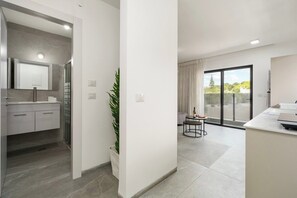 Een moderne keuken met een ingebouwde oven, een eethoek met een ronde tafel en een grote schuifpui naar een balkon.