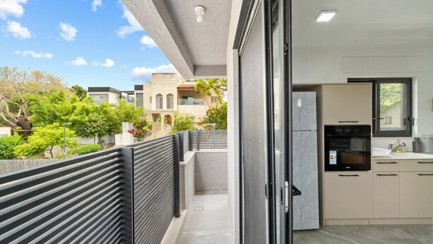A modern kitchen with a built-in oven and a view of a balcony with a railing.