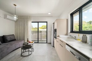 Een moderne keuken met een groot raam, een eethoek met tafel en stoelen, en een bank.