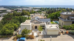 Zona residencial con una casa que tiene garaje, piscina y vista al mar.