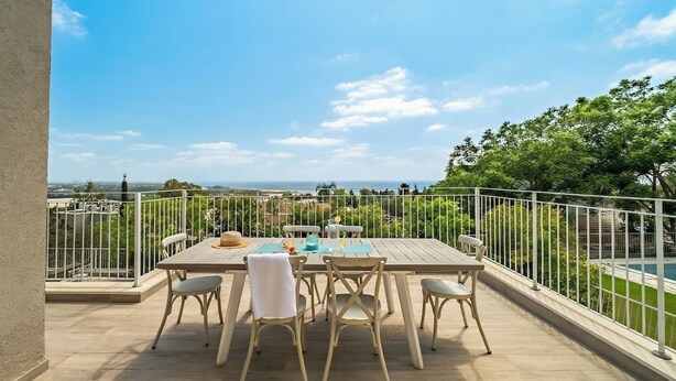 Una terraza con mesa y sillas, vistas a la ciudad y una piscina al fondo.
