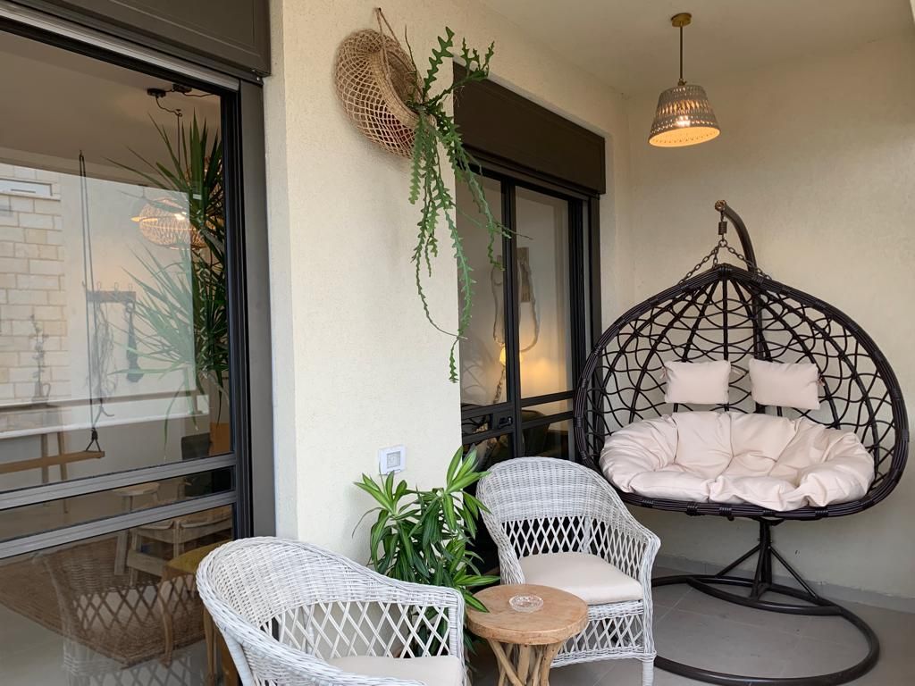 Ein Balkon mit Korbmöbeln, einer Hängematte und Blumentöpfen.