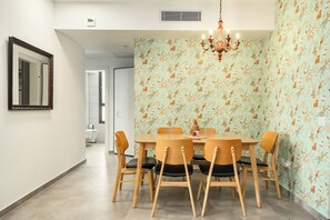 Un coin repas avec une table ronde, six chaises et un lustre.