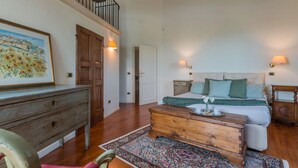 Une chambre spacieuse avec un grand lit, une commode en bois et un escalier menant à un niveau supérieur.