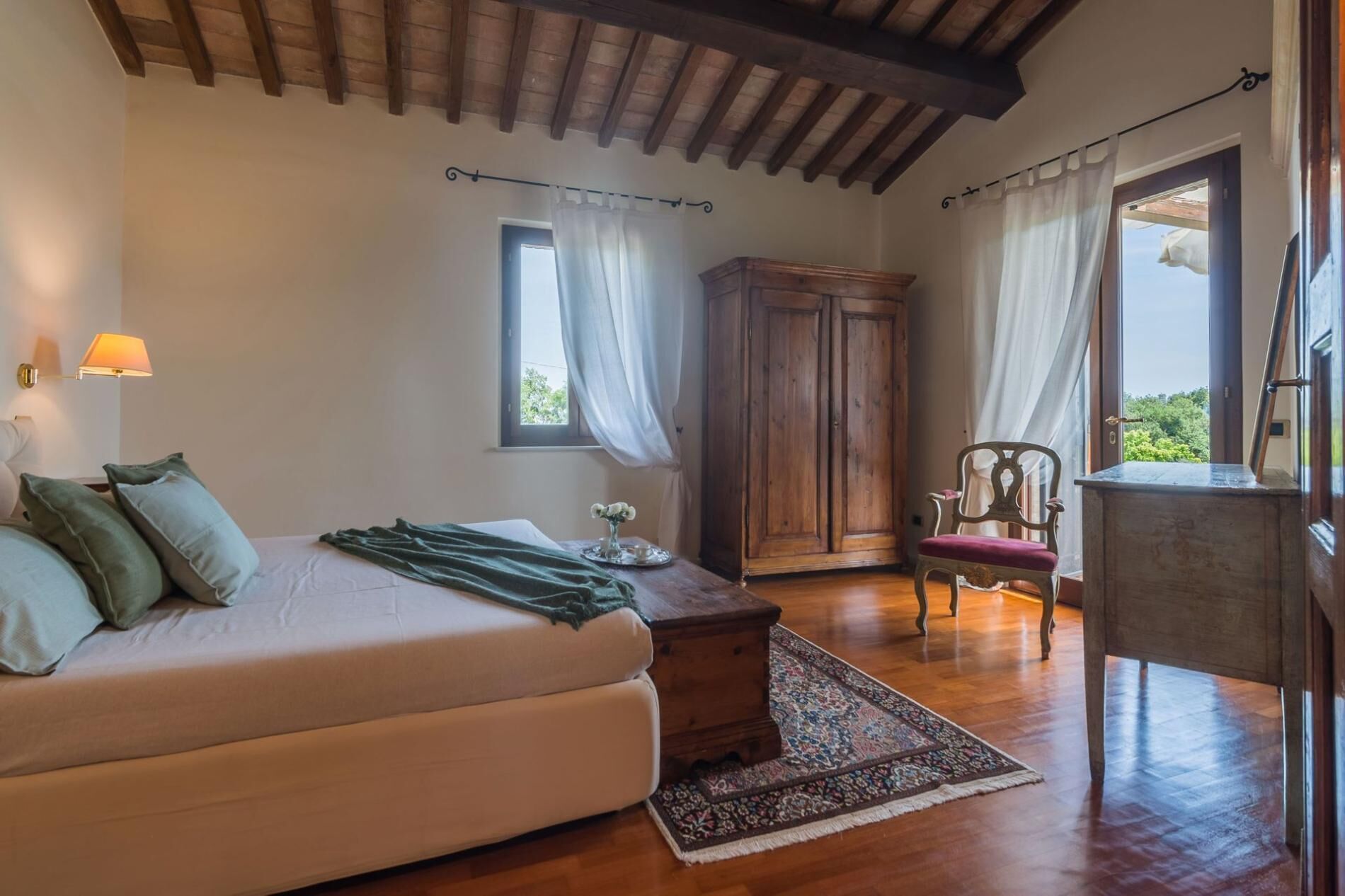 A cozy room with a bed, a wooden cabinet, a chair, and a desk.